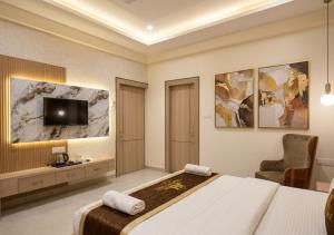 a bedroom with a bed and a tv on the wall at Hotel Atlantiis Suites By Signature StayZ Rathyatra Near Vishwanath Temple in Varanasi