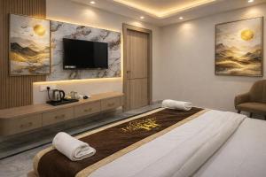 a bedroom with a large bed with a tv on the wall at Hotel Atlantiis Suites By Signature StayZ Rathyatra Near Vishwanath Temple in Varanasi +16 photos