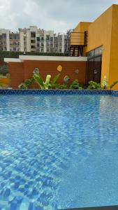 a large blue swimming pool in front of a building at Sofitel Caravanserai 1BHK Noida, Spectrum Mall Sector 75 in Noida