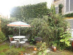 a table and chairs with an umbrella in a garden at Jardin et Hotel Particulier in Bayeux