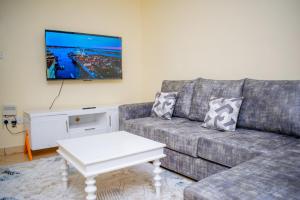 a living room with a couch and a tv on the wall at bluemoon in Watamu
