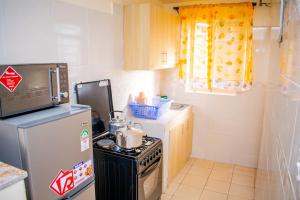a small kitchen with a stove and a refrigerator at bluemoon in Watamu