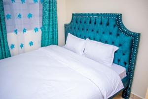 a bedroom with a white bed with a blue headboard at bluemoon in Watamu