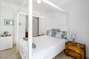 a white bedroom with a large white bed and a table at Comfort on Cabot in Edenvale