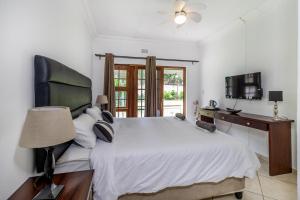 a bedroom with a bed and a desk and a television at Comfort on Cabot in Edenvale +14 photos