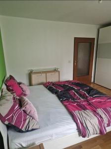 a bed with pink and black sheets and pillows at Schönes Doppelzimmer in Allmannshofen