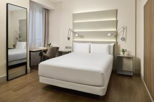 a bedroom with a large white bed and a desk at NH Sants Barcelona in Barcelona