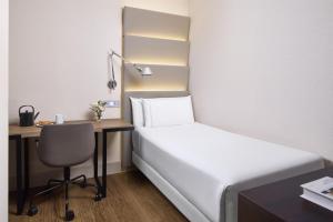 a bedroom with a bed and a desk with a chair at NH Sants Barcelona in Barcelona +42 photos