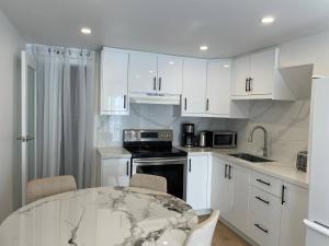 a kitchen with white cabinets and a marble table at Oshawa Suite Open Kitchen Living Space in Oshawa