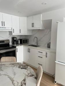 a kitchen with white cabinets and a sink and a table at Oshawa Suite Open Kitchen Living Space in Oshawa +10 photos