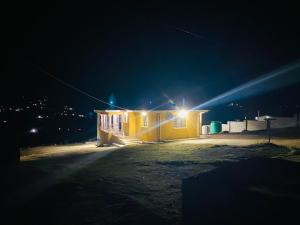 a yellow building with a light on it at night at R&N Hosts Mokhotlong in Mokoeng