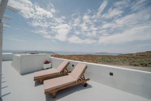 a balcony with two chairs and a view of the desert at Caldera's Elements in Santorini