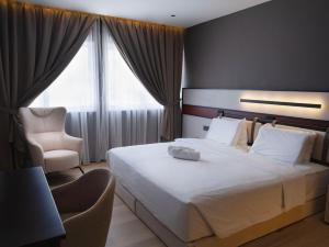 a bedroom with a large white bed and a chair at Merchant Hotel in George Town