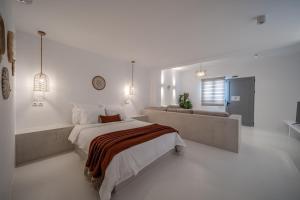 a white bedroom with a large bed and a couch at Caldera's Elements in Santorini +40 photos