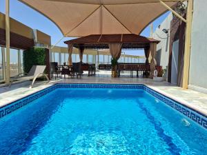 a swimming pool with an umbrella and a table and chairs at Areen Almatar Serviced Apartments شقق ارين المطار للشقق المخدومة in Jeddah