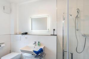 a white bathroom with a sink and a shower at Haus Seeluft - W4 in Butjadingen