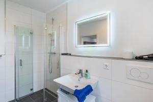 a white bathroom with a sink and a mirror at Haus Seeluft - W5 in Butjadingen