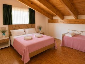 a bedroom with two beds with pink sheets at The Queen Oak - nature relais in Santa Marina +11 photos