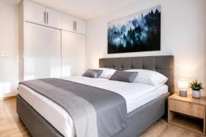 a bedroom with a large bed and a painting on the wall at Evergreen Tale Apartman F2 in Tale