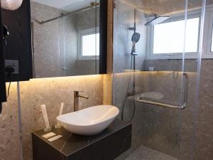 a bathroom with a sink and a glass shower at Merchant Hotel in George Town