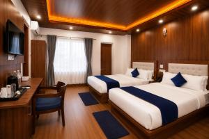 a hotel room with two beds and a desk and a desk at Hotel happy stay inn in Pashupatināth