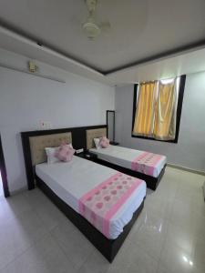 two beds in a hotel room with pink and white sheets at Karma Bodhgaya in Bodh Gaya