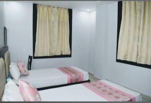 a bedroom with two beds and two windows at Karma Bodhgaya in Bodh Gaya
