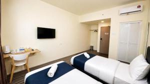 a hotel room with two beds and a desk at Hotel Seri Warisan Melaka in Malacca