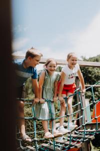 a group of three children standing on top of a fence at Lerchs Landhotel in Sankt Johann im Pongau