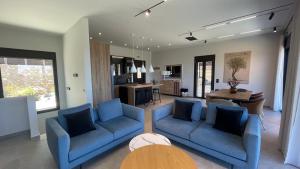 a living room with two blue couches and a kitchen at Carmelia Villas in Agios Nikitas
