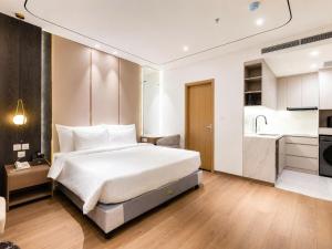 a bedroom with a large white bed and a kitchen at Sunshine Grand Hotel in Móng Cái +46 photos