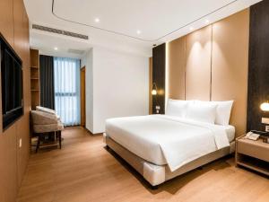 a bedroom with a large white bed and a television at Sunshine Grand Hotel in Móng Cái