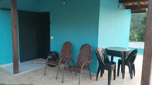 a patio with chairs and a table and a blue wall at Cantinho RMA in Bom Jesus dos Perdões