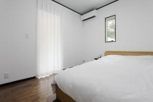 a bedroom with a white bed and a window at ピッコラ カーサ コリーナ 愛犬と泊まれる貸別荘 in Awaji +14 photos