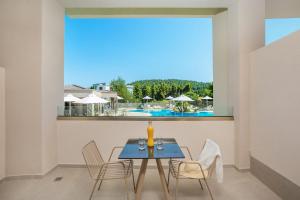 a dining room with a table and chairs and a large window at Anẽse Vacation Feelings in Paliouri