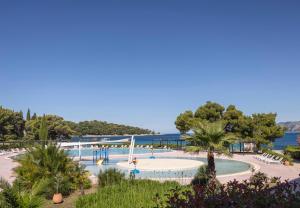 a large swimming pool in a park next to the water at Remisens Hotel Albatros-All inclusive in Cavtat