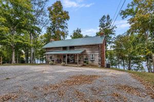 an old log house with a gravel driveway at Hickory Haven Cozy Lakefront Escape & Dock in Cadiz