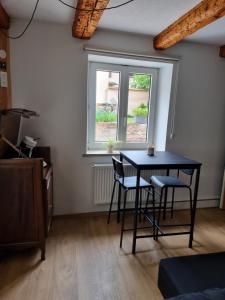 a table and chairs in a room with a window at pas de nom in Rosenwiller