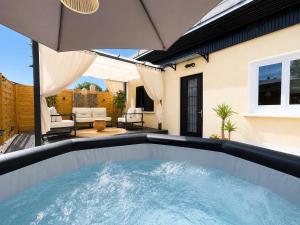 a hot tub in a backyard with an umbrella at Sweet Escape et Jacuzzi Privé in Gonesse