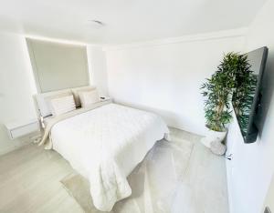 a white bedroom with a bed and a tv at Sweet Escape et Jacuzzi Privé in Gonesse