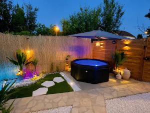 a backyard with a hot tub and an umbrella at Sweet Escape et Jacuzzi Privé in Gonesse