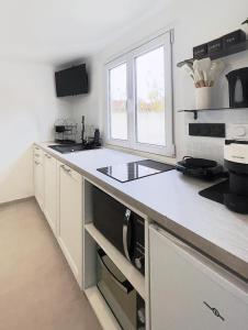 a white kitchen with a stove and a sink at Sweet Escape et Jacuzzi Privé in Gonesse