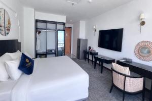 a hotel room with a white bed and a television at Sandals Everyday Hotel in Tuy Hoa