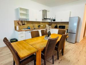 a kitchen with a wooden table with chairs and a refrigerator at RheinZeit Apartment Köln Bonn in Niederkassel +13 photos