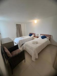 two beds in a room with a chair and a couch at Cormorani appartamento N 5 in Golfo Aranci