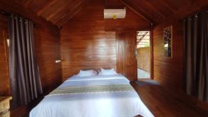 a bedroom with a bed in a wooden room at FURUSATO BUNGALOW Gili Gede in Gili Gede
