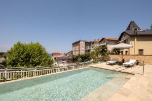 a swimming pool with two chairs and a fence at Eurostars Villa Itziar in San Sebastián