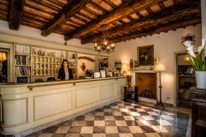 a woman standing behind a counter in a room with a fireplace at Hotel Cavalieri Del Mare in Marina di Massa