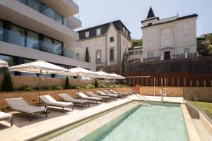 a pool with chairs and umbrellas next to a building at Eurostars Villa Itziar in San Sebastián