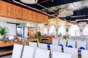 a dining room with white chairs and a bar at Sandals Everyday Hotel in Tuy Hoa